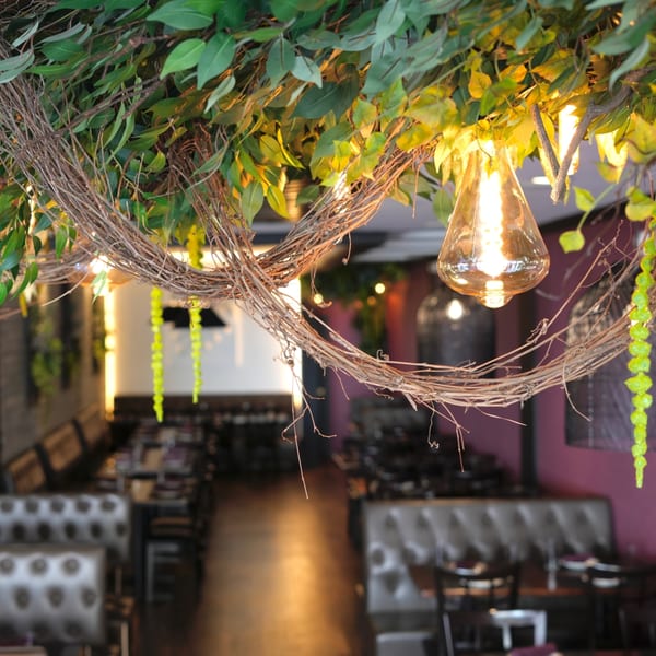 Decorative vines and leaves with Edison bulbs hanging over the Badageoni Georgian restaurant interior.
